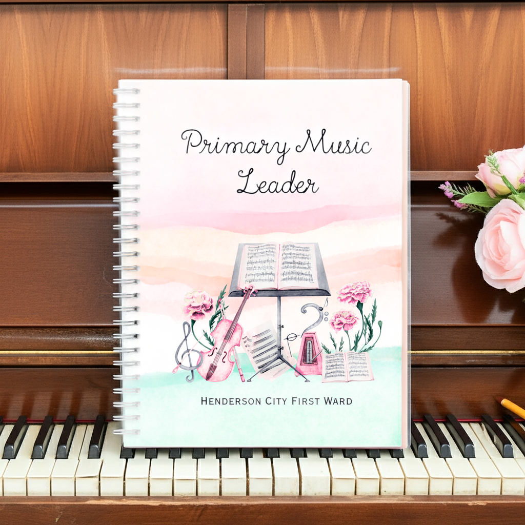 A spiral-bound notebook titled 'Primary Music Leader' with a pastel watercolor illustration of a violin, music stand, flowers, and sheet music, standing on a piano keyboard in front of a wooden piano.